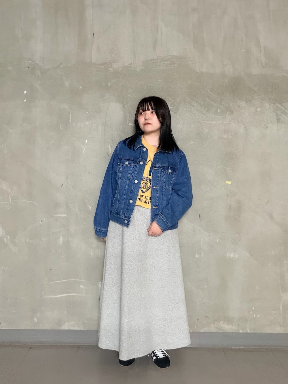 グレー系のスカート、イエロー系のTシャツ/カットソー、ブラック系のスニーカーを着用したレディースの春コーディネートの4枚目の写真