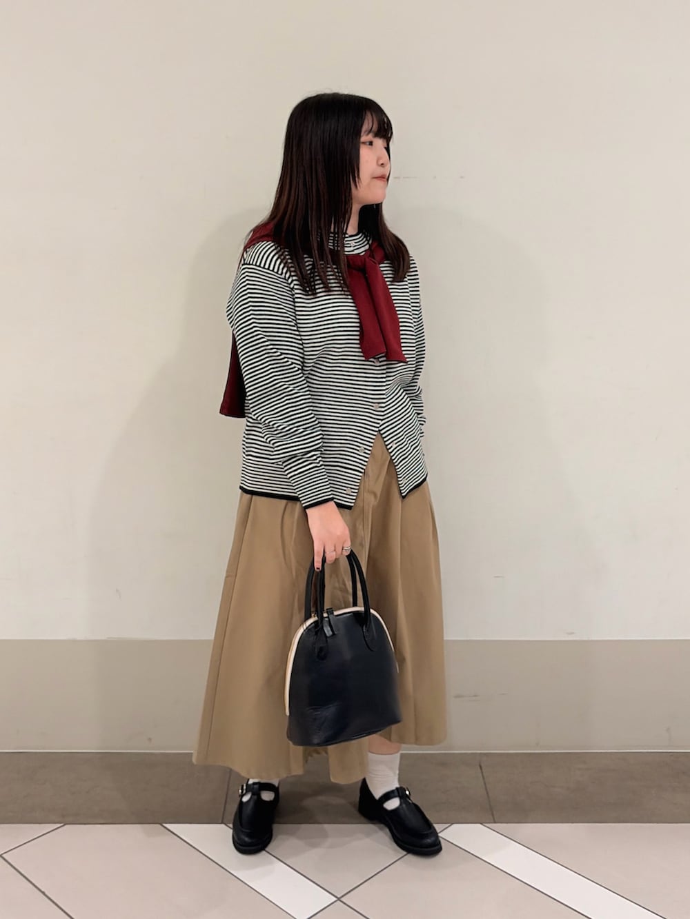 ブラック系のローファー、ホワイト系のカーディガン/ボレロ、ベージュ系のスカートを着用したレディースの秋コーディネートの2枚目の写真