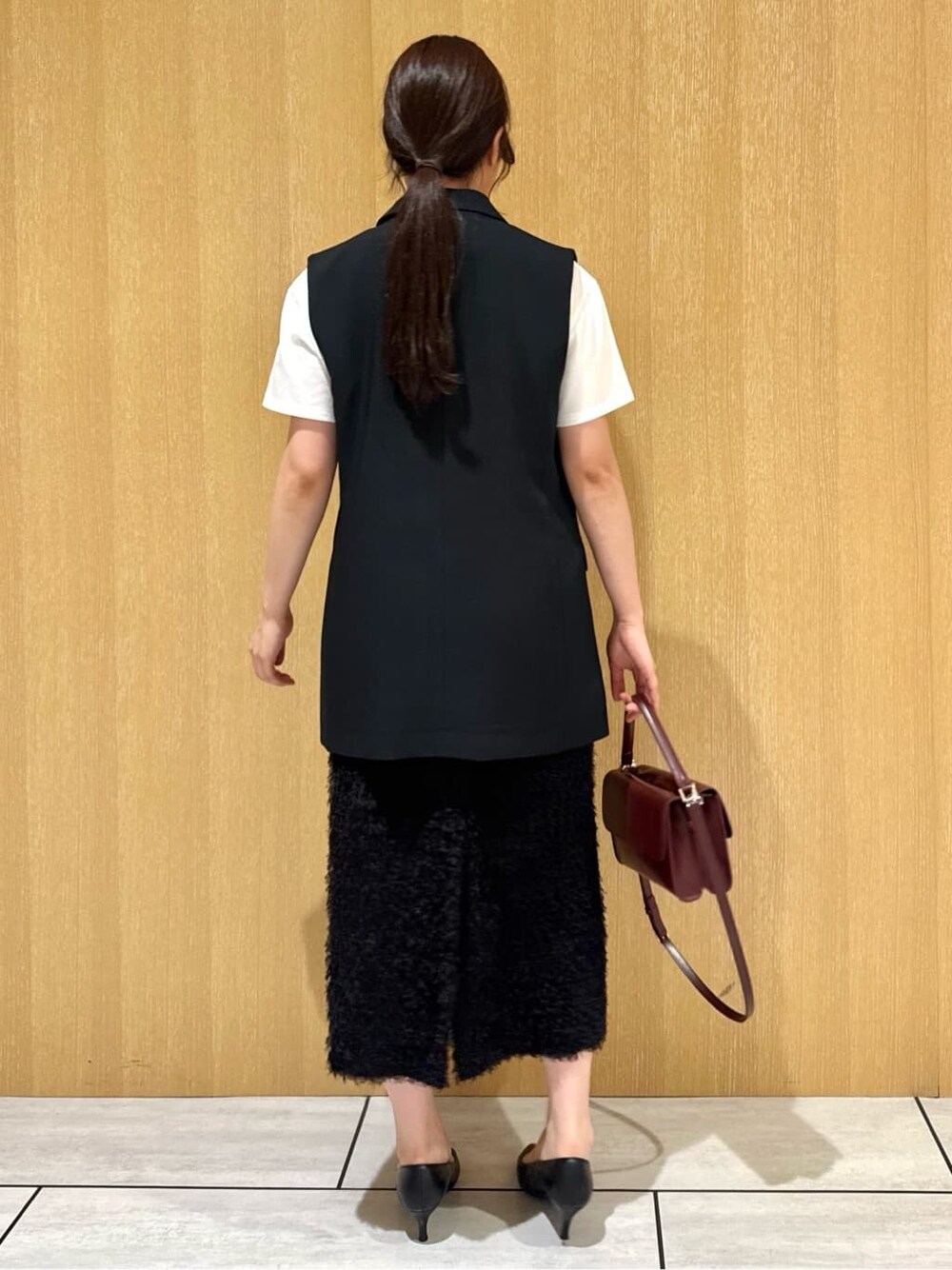 ブラック系のベスト、ホワイト系のTシャツ/カットソー、ブラウン系のスカートを着用したレディースの夏コーディネートの4枚目の写真
