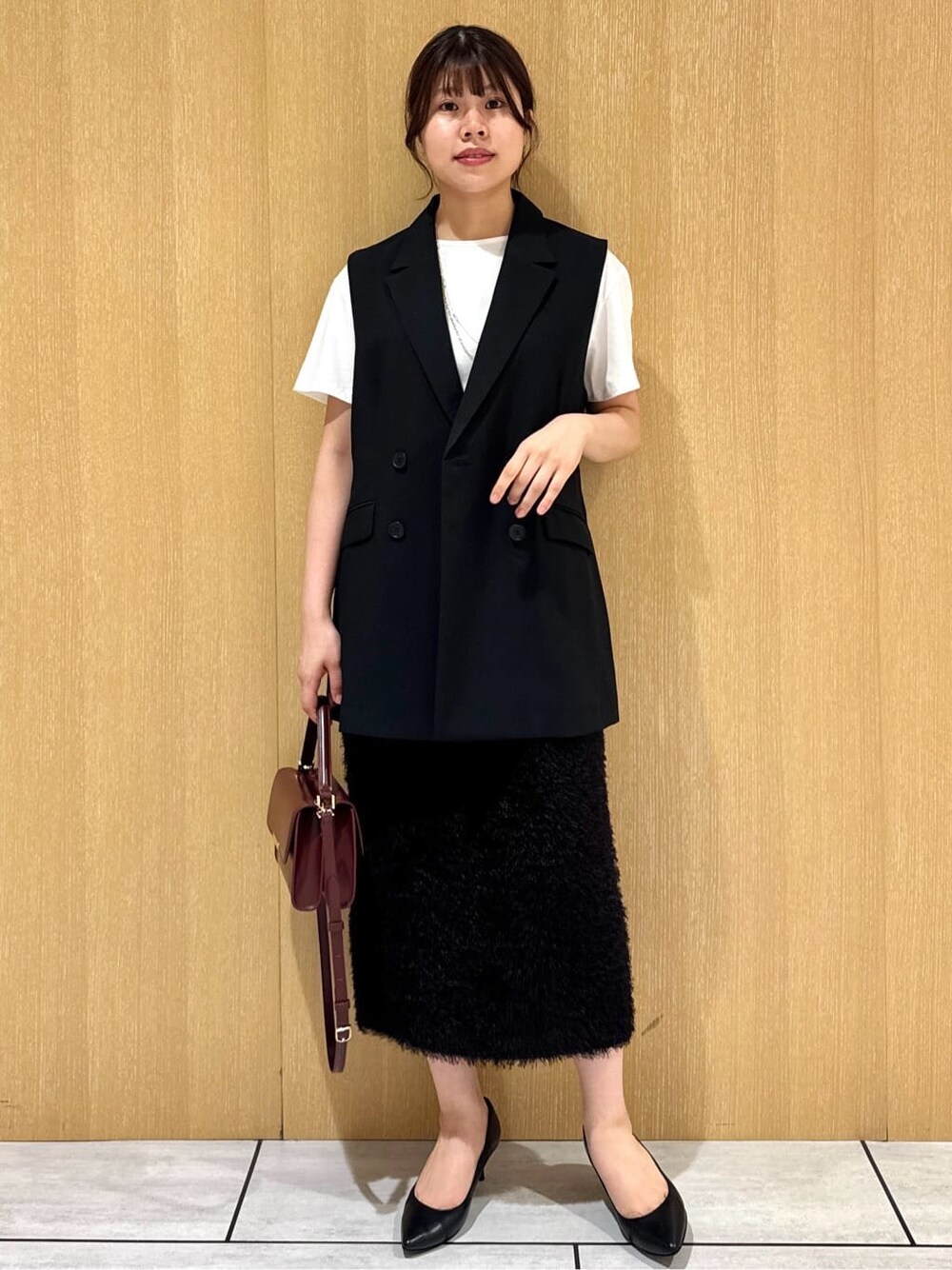 ブラック系のベスト、ホワイト系のTシャツ/カットソー、ブラウン系のスカートを着用したレディースの夏コーディネートの9枚目の写真