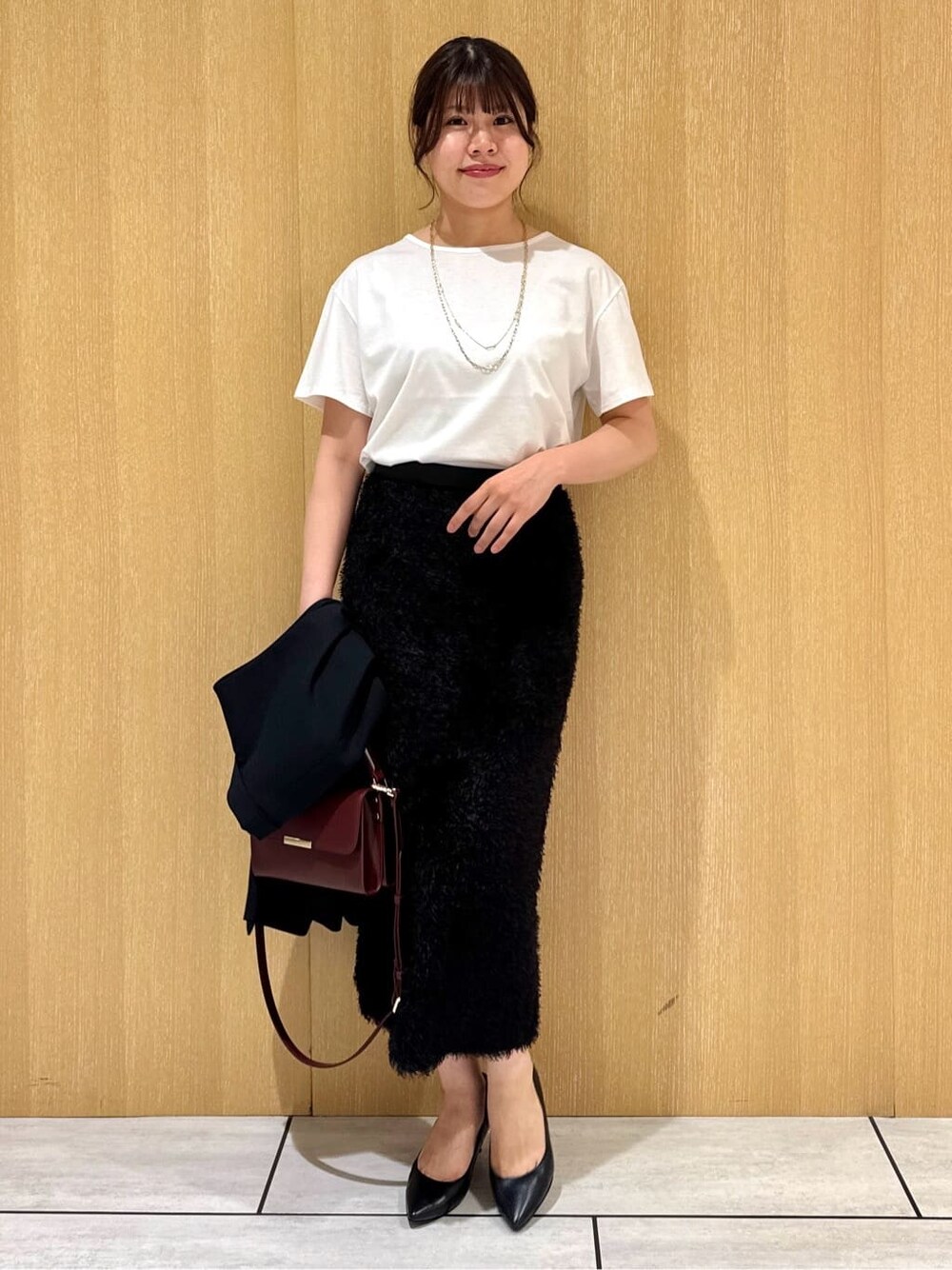 ブラック系のベスト、ホワイト系のTシャツ/カットソー、ブラウン系のスカートを着用したレディースの夏コーディネートの6枚目の写真