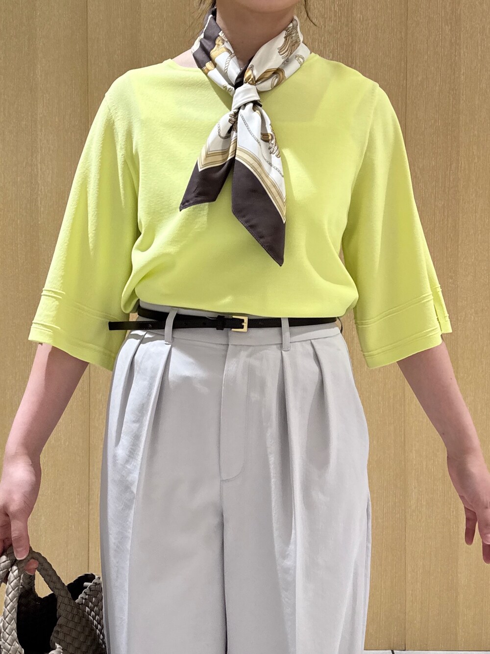 イエロー系のニット/セーター、ブラウン系のトートバッグ、グレー系のその他パンツを着用したレディースの春コーディネートの5枚目の写真