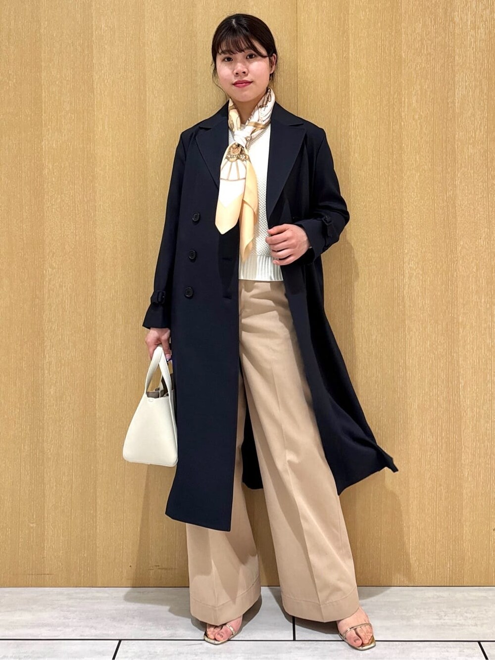 ホワイト系のニット/セーター、ベージュ系のその他パンツ、ブルー系のトレンチコートを着用したレディースの冬コーディネートの6枚目の写真