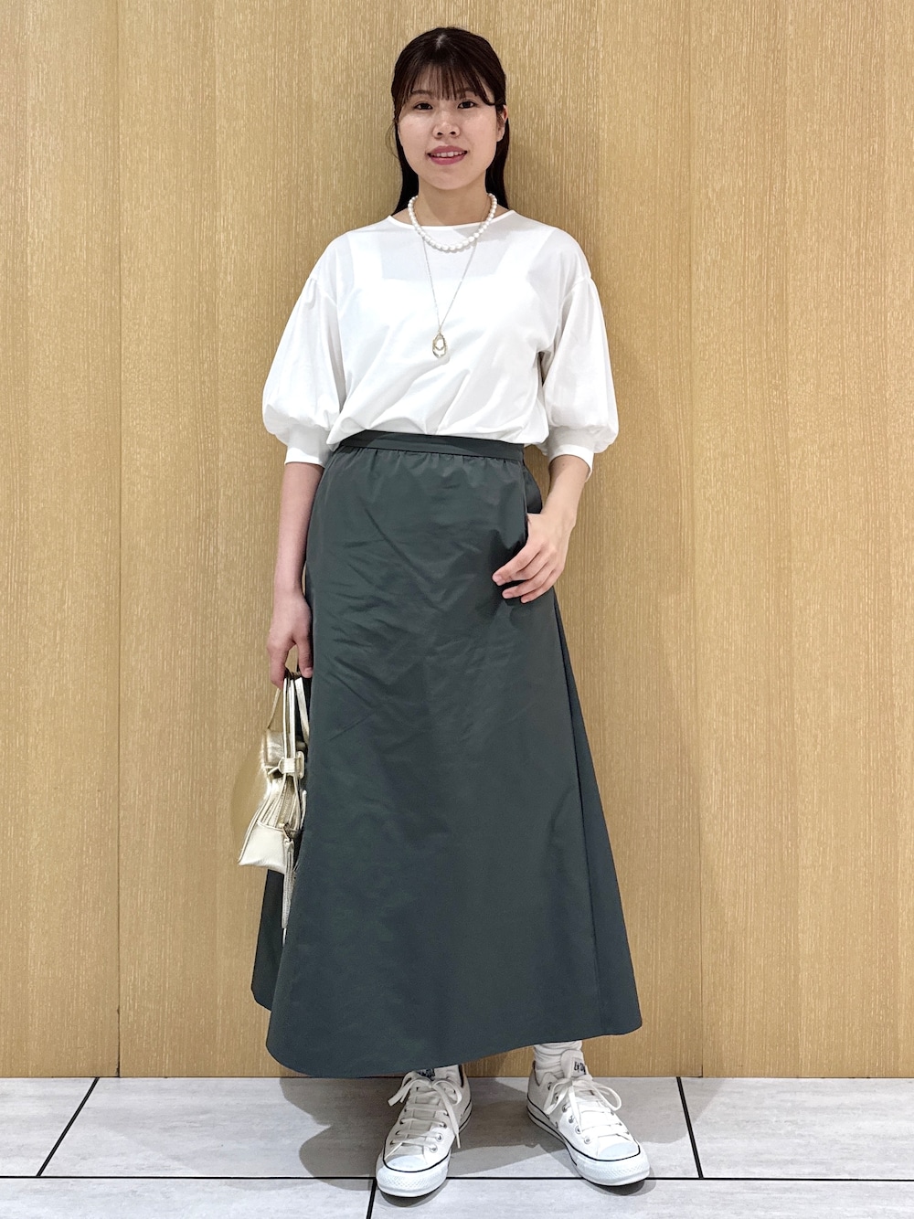 ホワイト系のTシャツ/カットソー、グリーン系のスカートを着用したレディースの秋コーディネートの2枚目の写真