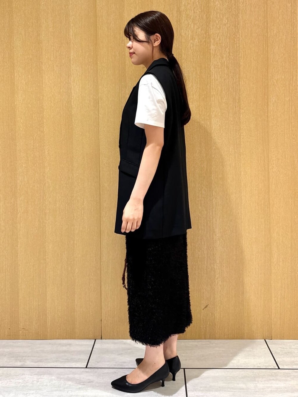 ブラック系のベスト、ホワイト系のTシャツ/カットソー、ブラウン系のスカートを着用したレディースの夏コーディネートの3枚目の写真