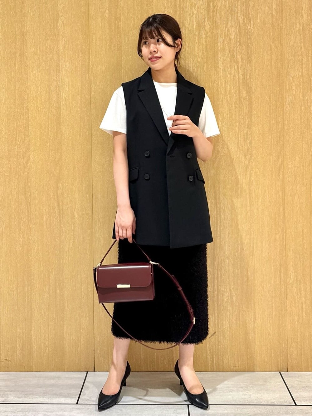ブラック系のベスト、ホワイト系のTシャツ/カットソー、ブラウン系のスカートを着用したレディースの夏コーディネートの7枚目の写真