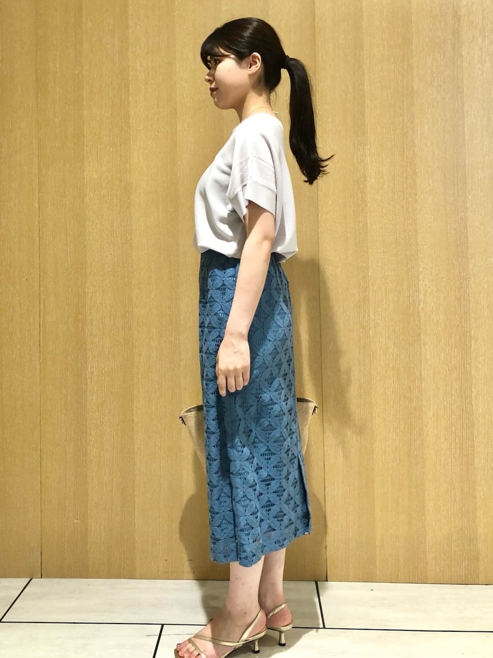 グレー系のニット/セーター、ブルー系のスカートを着用したレディースの夏コーディネートの2枚目の写真