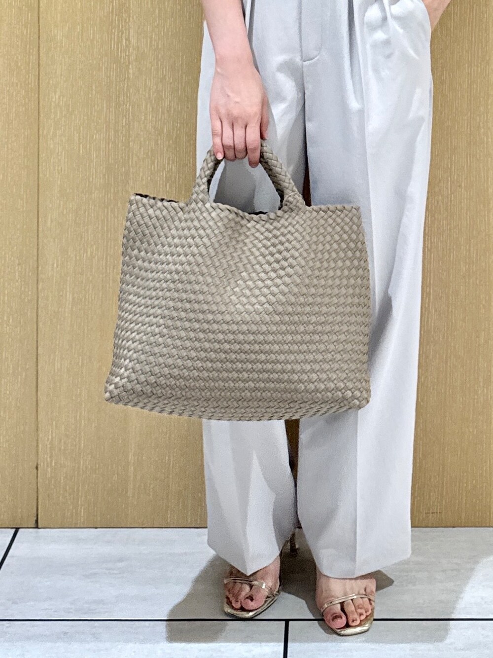 イエロー系のニット/セーター、ブラウン系のトートバッグ、グレー系のその他パンツを着用したレディースの春コーディネートの7枚目の写真