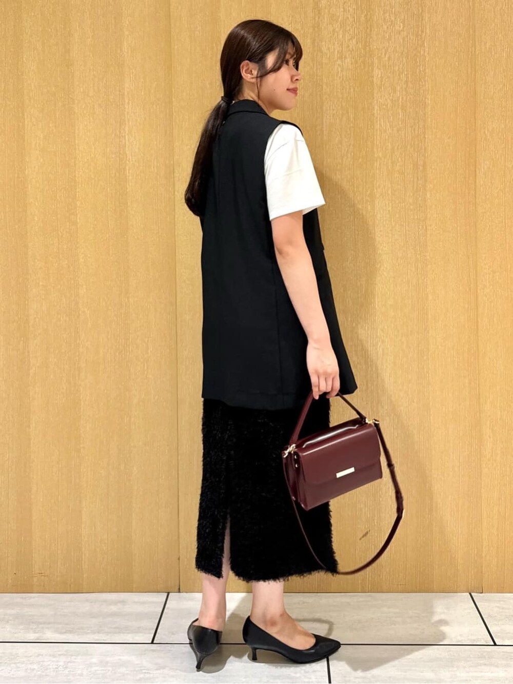ブラック系のベスト、ホワイト系のTシャツ/カットソー、ブラウン系のスカートを着用したレディースの夏コーディネートの5枚目の写真