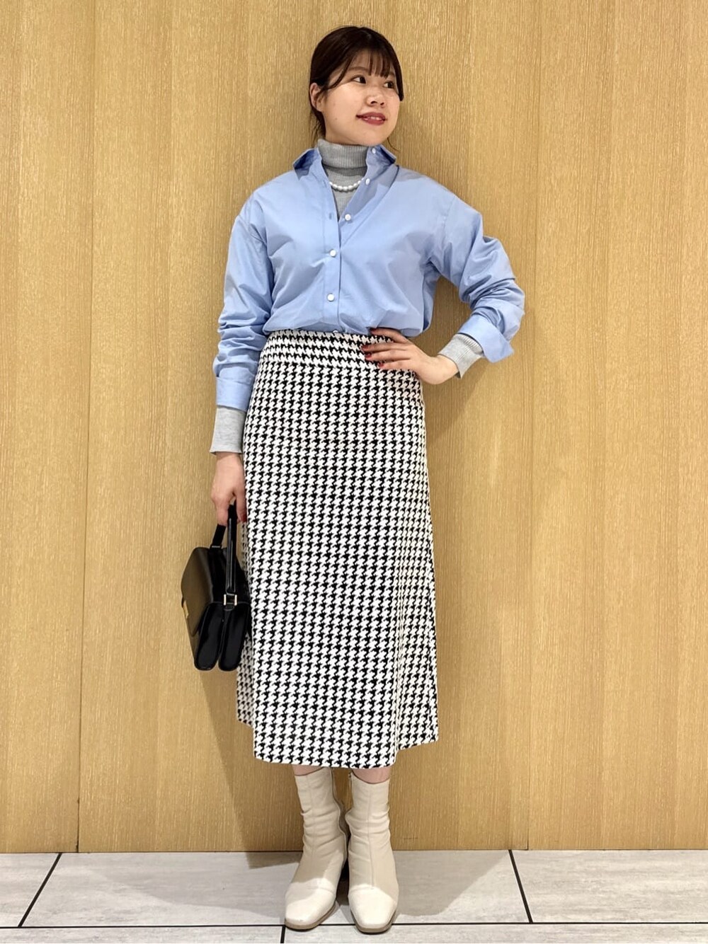 グレー系のニット/セーター、ブラック系のスカート、ブルー系のシャツ/ブラウスを着用したレディースの冬コーディネートの7枚目の写真
