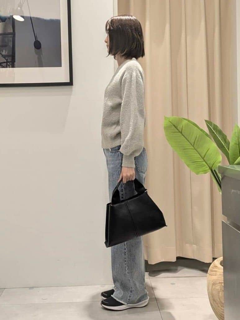 ベージュ系のニット/セーター、ブルー系のデニムパンツ、ブラック系のショルダーバッグを着用したレディースの秋コーディネートの4枚目の写真