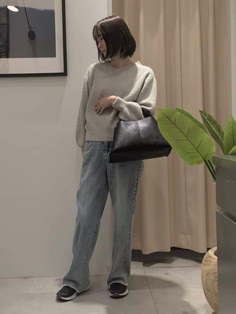 ベージュ系のニット/セーター、ブルー系のデニムパンツ、ブラック系のショルダーバッグを着用したレディースの秋コーディネートの2枚目の写真