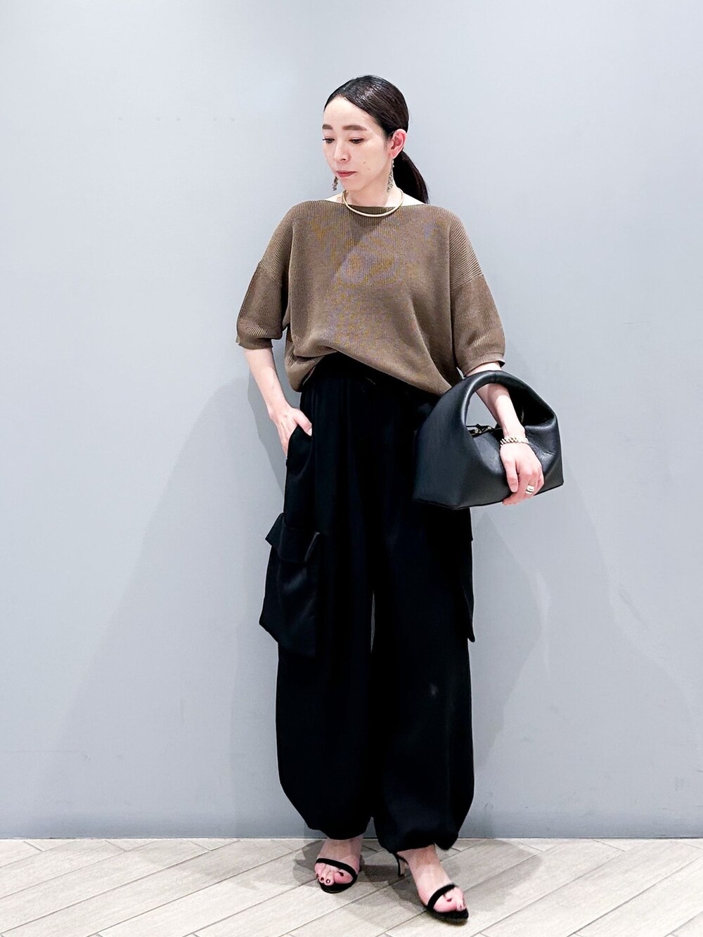 ブラック系のその他パンツ、ブラウン系のニット/セーター、ブラック系のハンドバッグを着用したレディースの春コーディネートの2枚目の写真