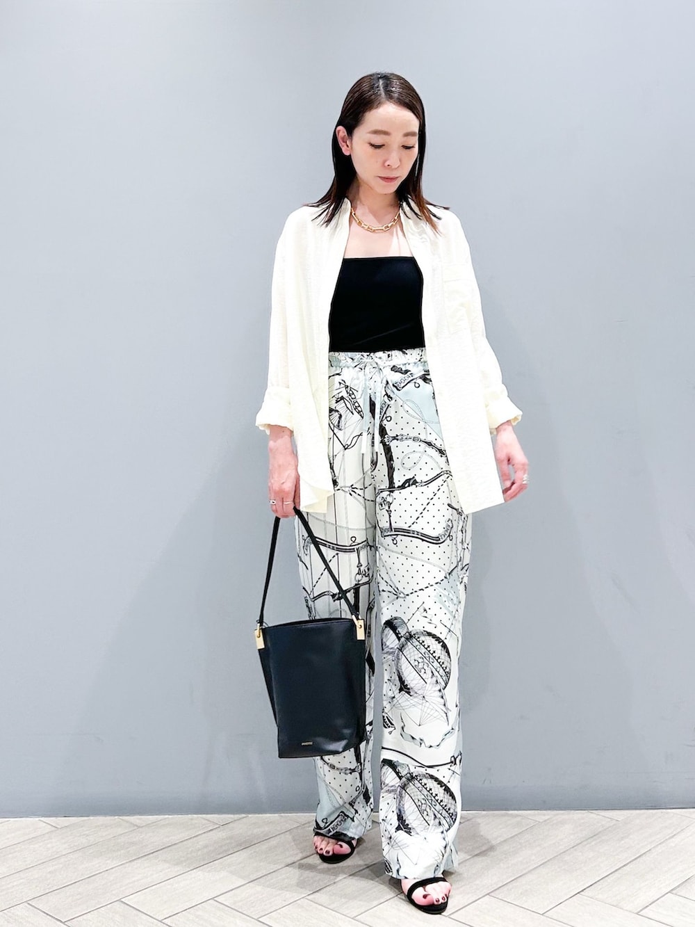 グレー系のその他パンツ、ホワイト系のシャツ/ブラウス、ブラック系のショルダーバッグを着用したレディースの夏コーディネートの2枚目の写真