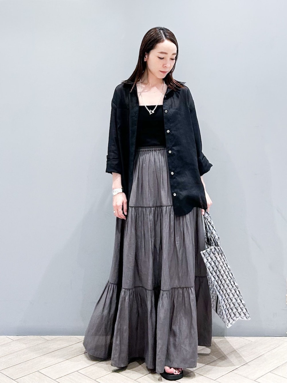 ブラック系のシャツ/ブラウス、グレー系のスカート、ブラック系のサンダルを着用したレディースの夏コーディネートの2枚目の写真