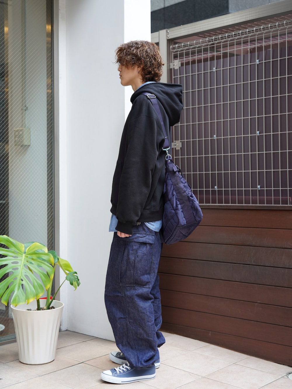 ブラック系のパーカー、ブルー系のカーゴパンツ、ブルー系のスニーカーを着用したメンズの冬コーディネートの2枚目の写真