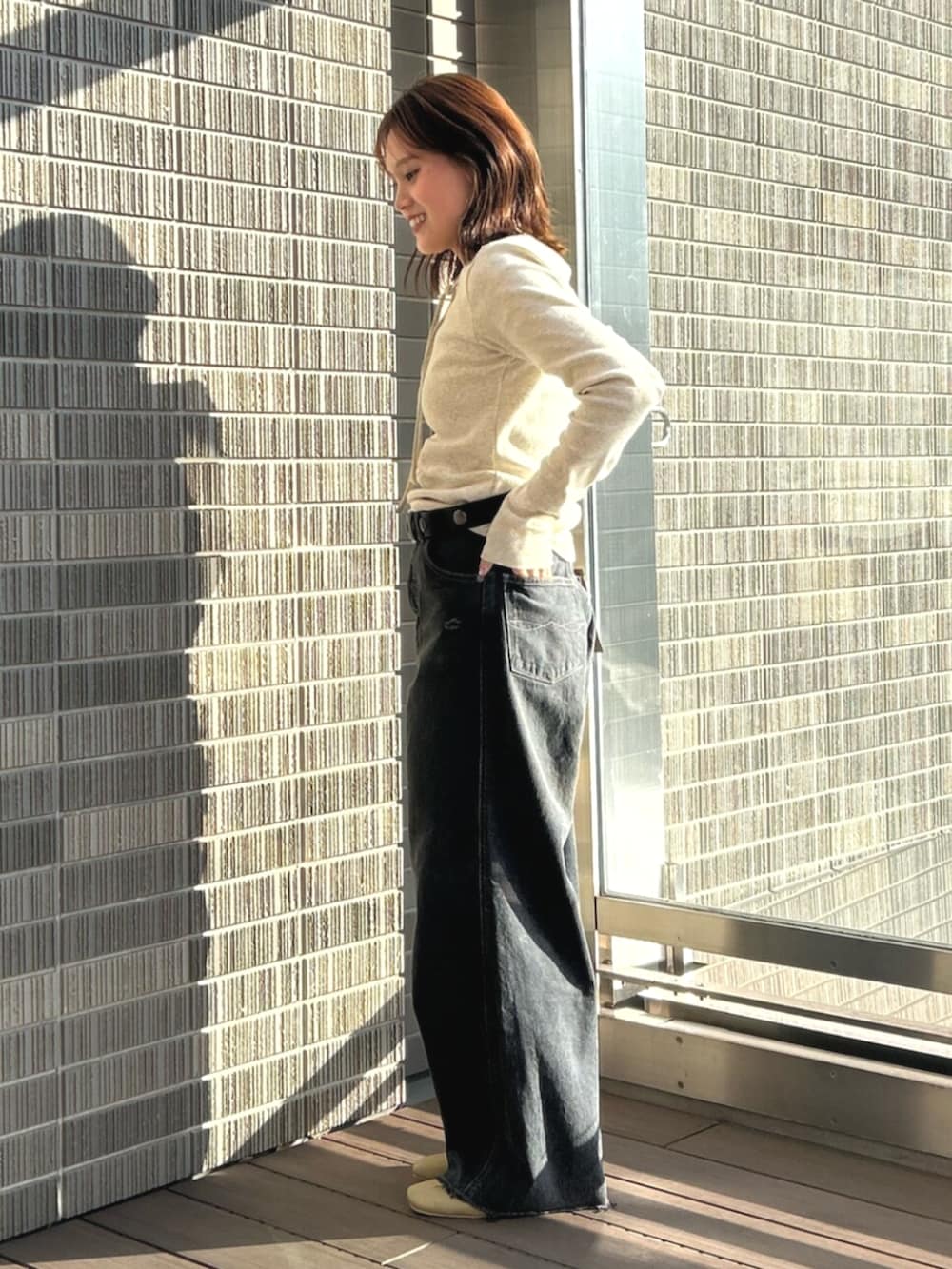 ブラック系のデニムパンツ、グレー系のTシャツ/カットソー、イエロー系のサンダルを着用したレディースの春コーディネートの2枚目の写真