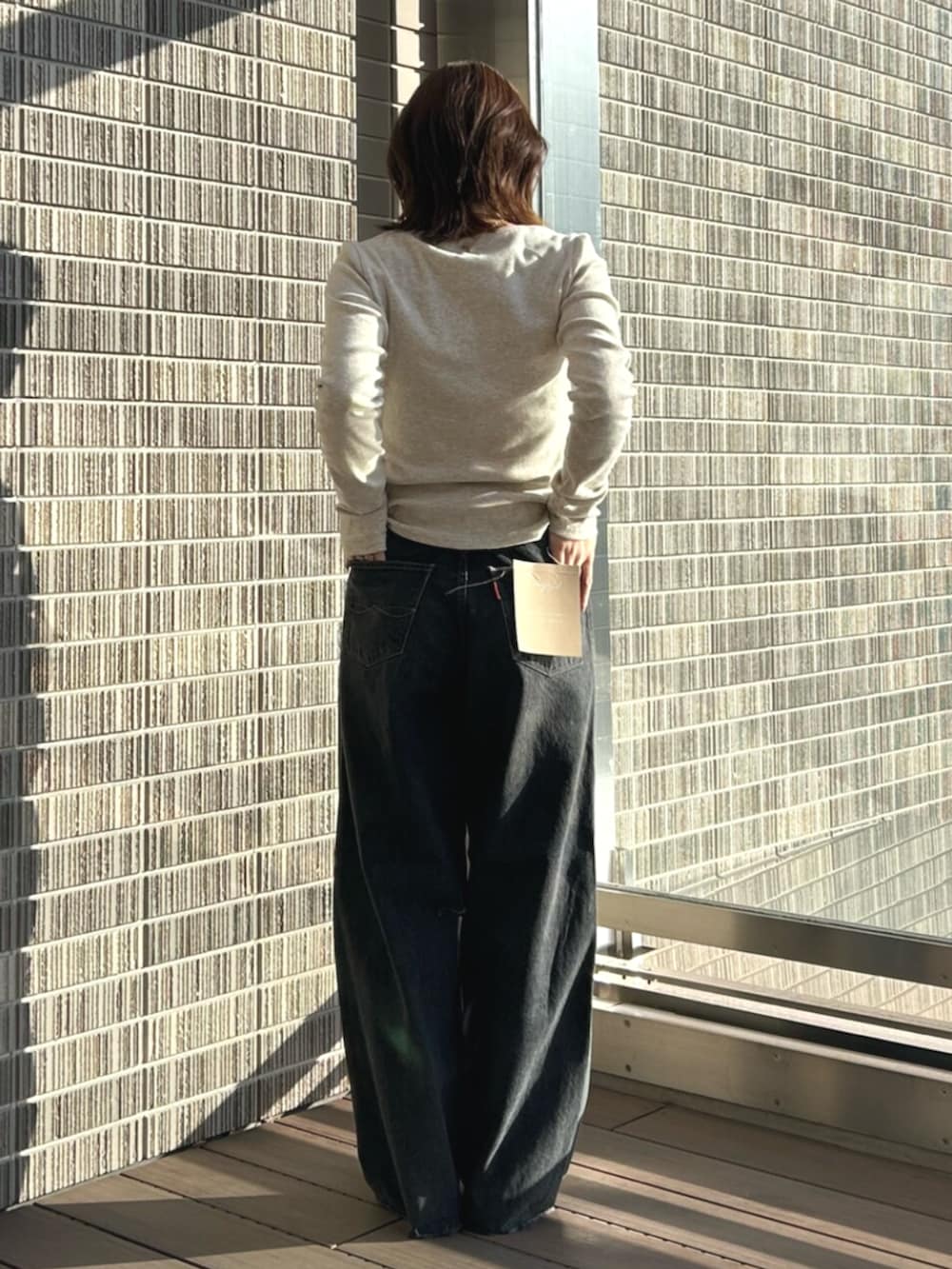 ブラック系のデニムパンツ、グレー系のTシャツ/カットソー、イエロー系のサンダルを着用したレディースの春コーディネートの3枚目の写真