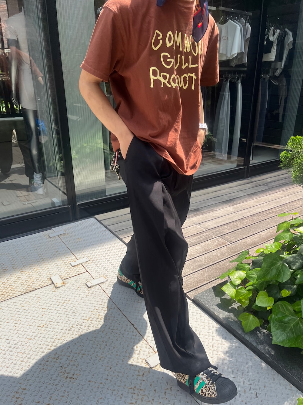 ブラウン系のTシャツ/カットソー、ブラック系のスラックス、グリーン系のスニーカーを着用したメンズの秋コーディネートの2枚目の写真