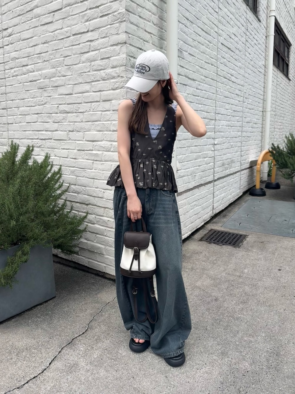 ブラック系のシャツ/ブラウス、ホワイト系のキャップを着用したレディースの春コーディネートの2枚目の写真