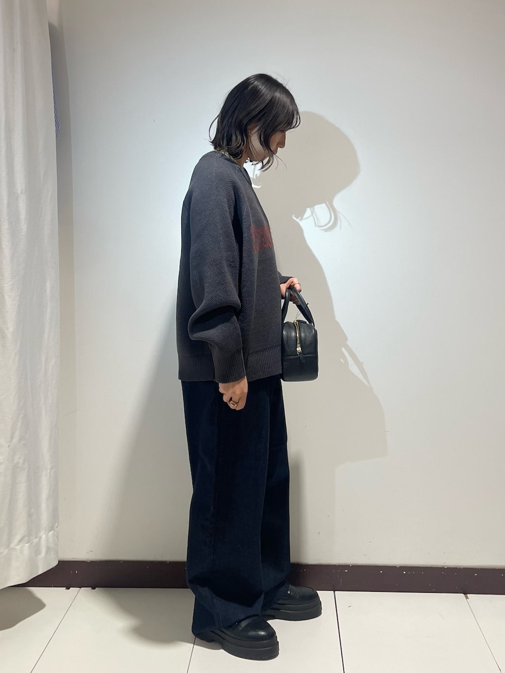 グレー系のニット/セーター、ブラック系のボストンバッグ、ブルー系のデニムパンツを着用したレディースの冬コーディネートの4枚目の写真