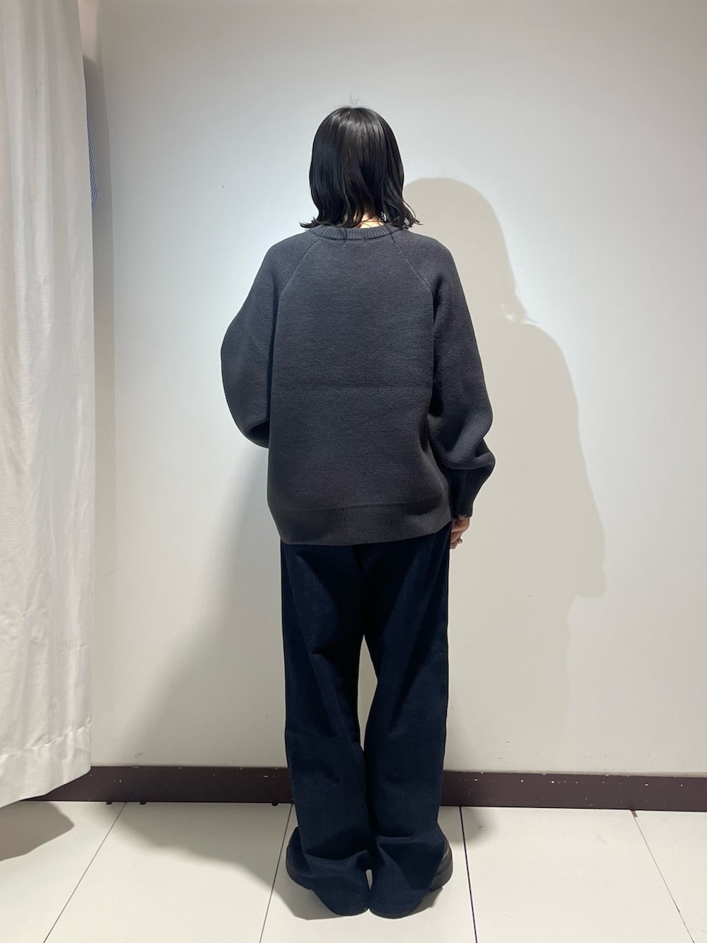 グレー系のニット/セーター、ブラック系のボストンバッグ、ブルー系のデニムパンツを着用したレディースの冬コーディネートの3枚目の写真