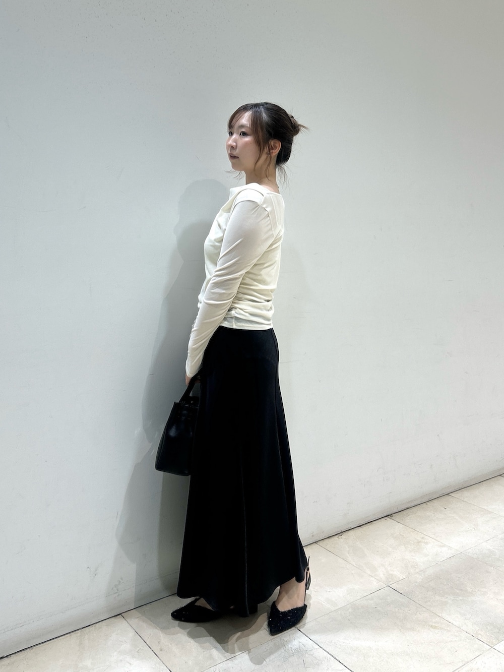 ブラック系のスカート、ブラック系のトートバッグ、ホワイト系のTシャツ/カットソーを着用したレディースの秋コーディネートの4枚目の写真