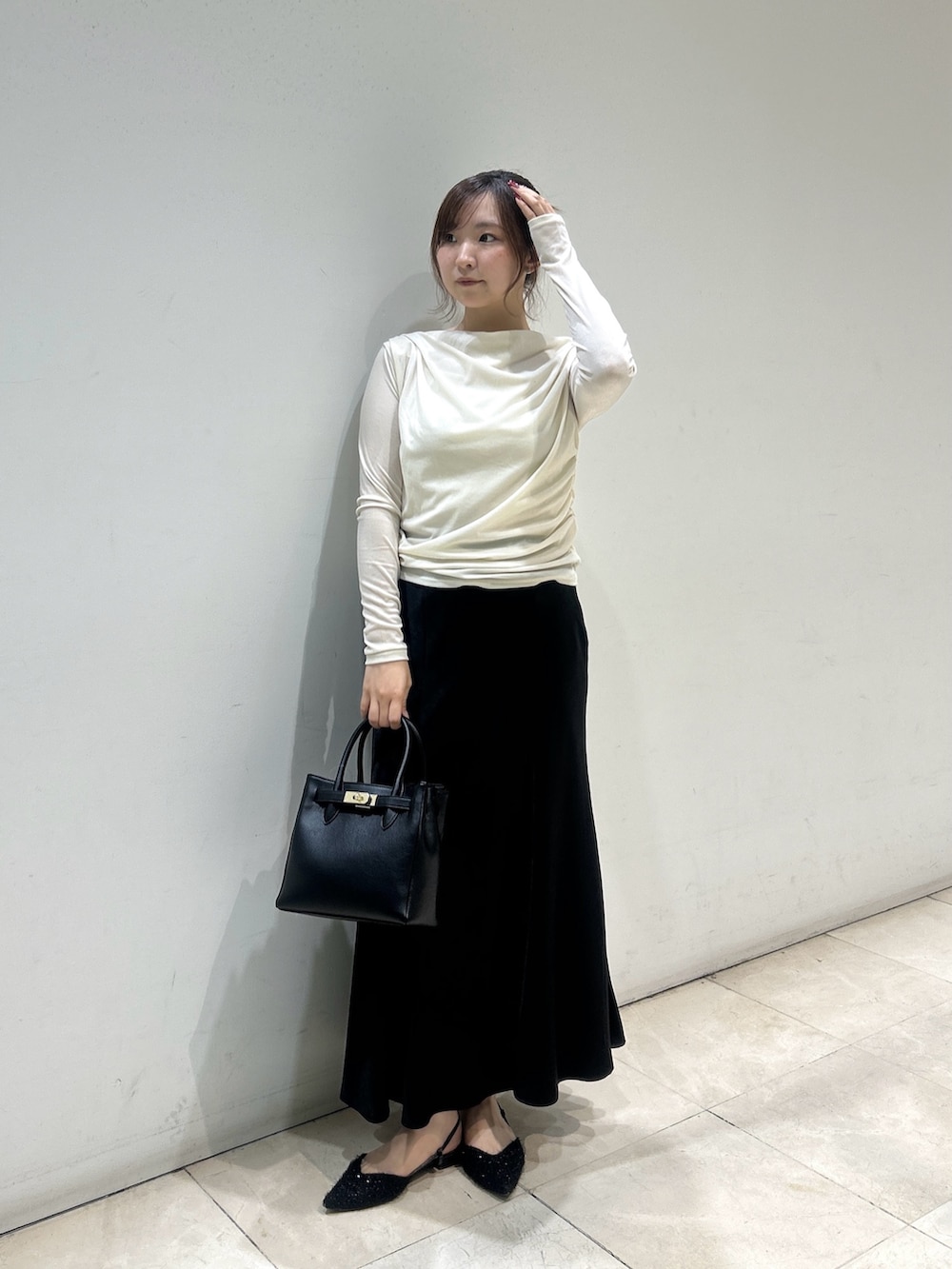 ブラック系のスカート、ブラック系のトートバッグ、ホワイト系のTシャツ/カットソーを着用したレディースの秋コーディネートの3枚目の写真