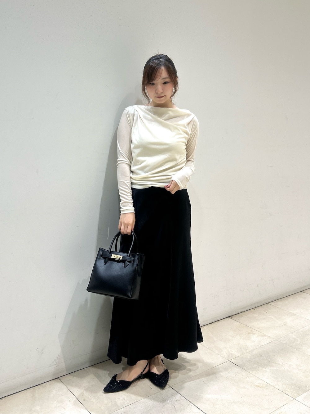 ブラック系のスカート、ブラック系のトートバッグ、ホワイト系のTシャツ/カットソーを着用したレディースの秋コーディネートの2枚目の写真