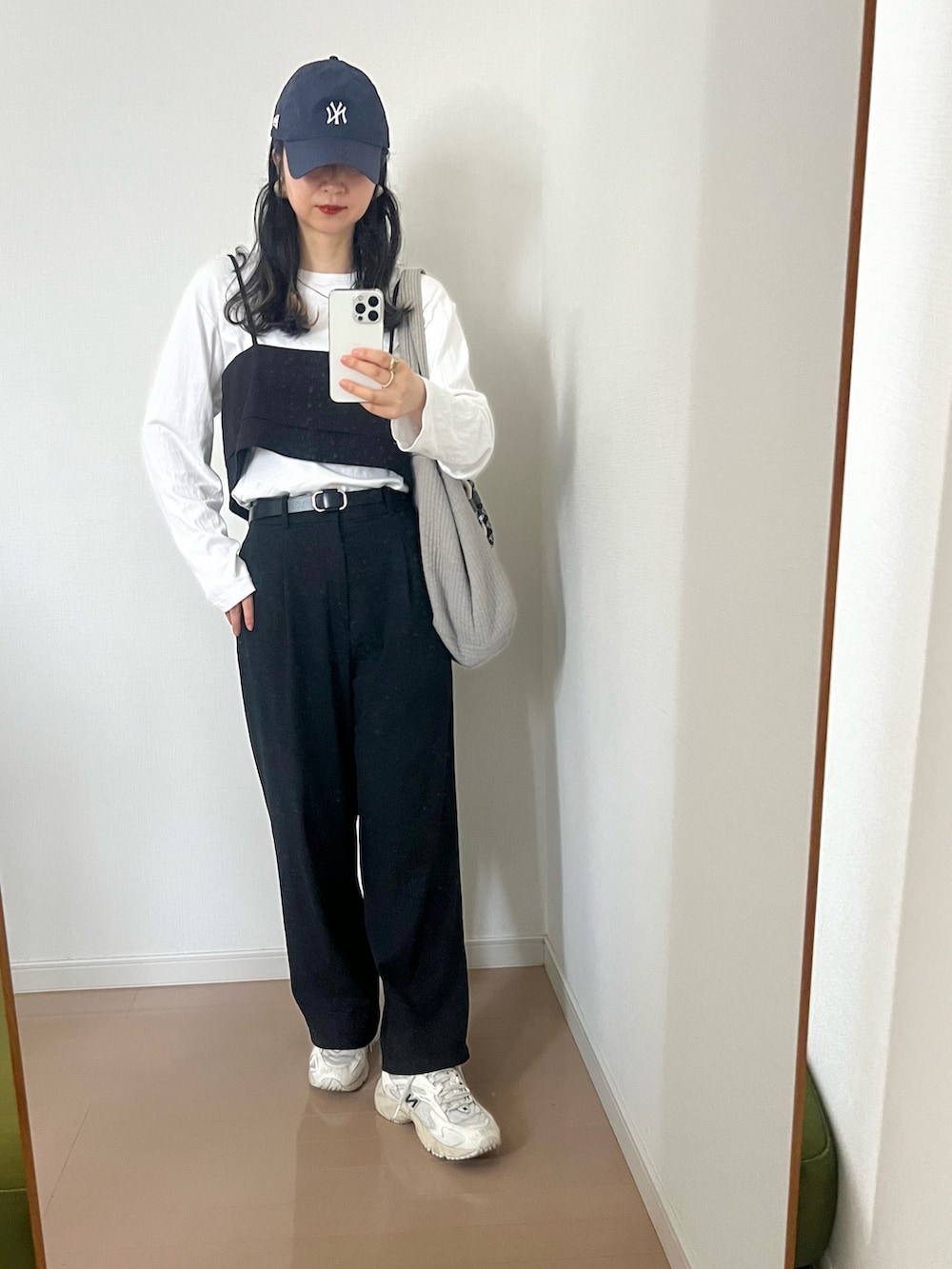 ブラック系のベスト、ホワイト系のTシャツ/カットソー、ブラック系のスラックスを着用したレディースの春コーディネートの2枚目の写真