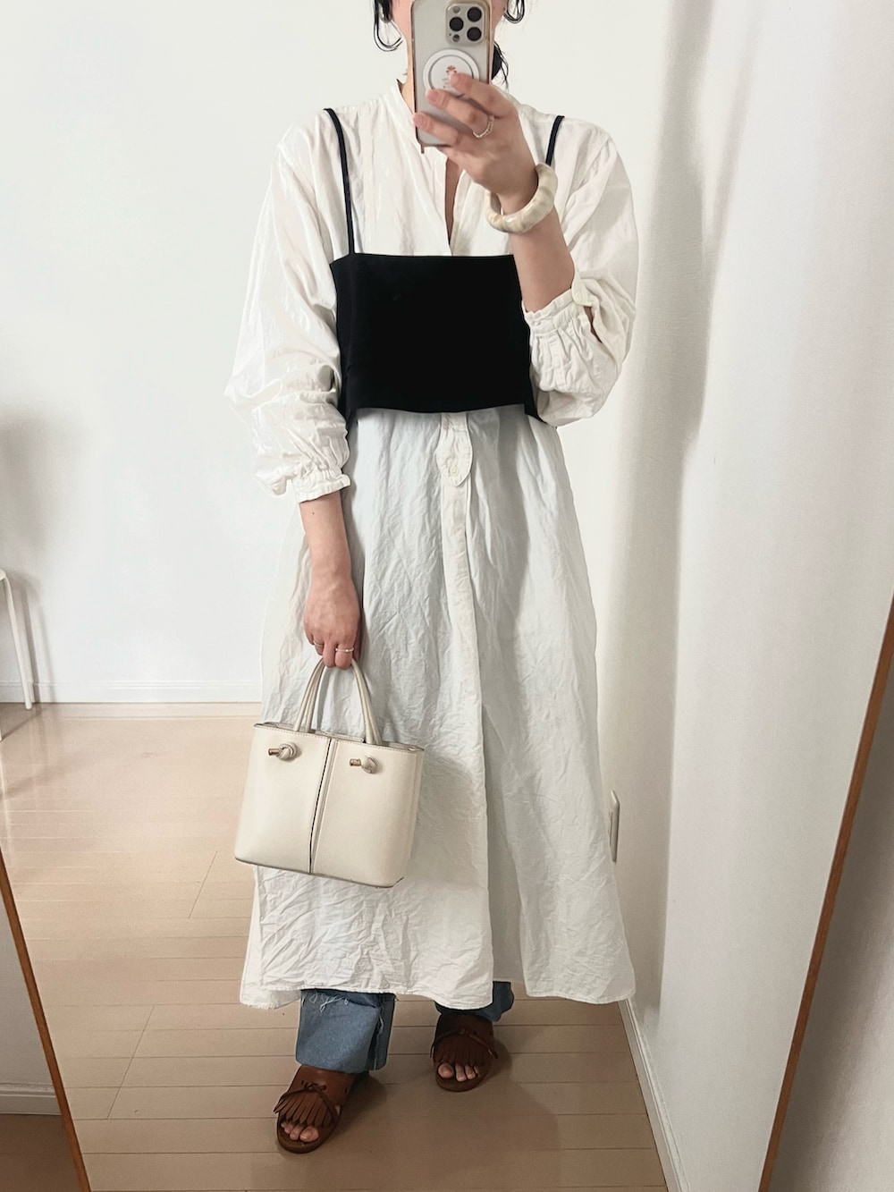 ブルー系のデニムパンツ、ブラック系のベスト、ホワイト系のシャツワンピースを着用したレディースの夏コーディネートの2枚目の写真