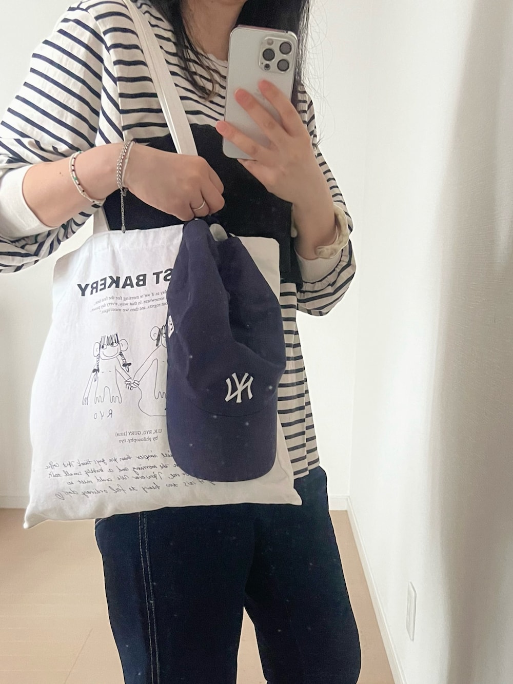 ブルー系のデニムパンツ、ブラック系のベスト、ホワイト系のTシャツ/カットソーを着用したレディースの春コーディネートの2枚目の写真