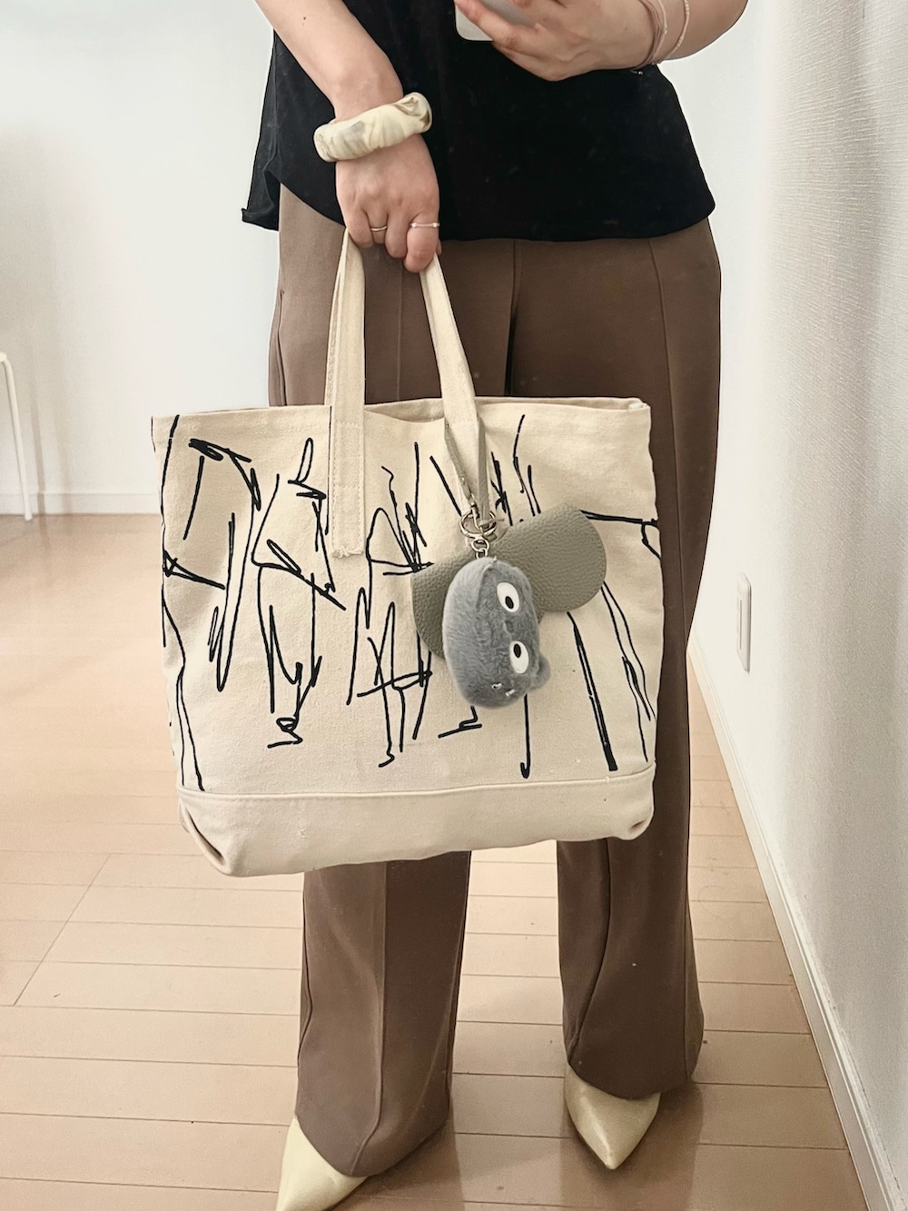 ブラック系のTシャツ/カットソー、ホワイト系のトートバッグ、ホワイト系のパンプスを着用したレディースの夏コーディネートの2枚目の写真