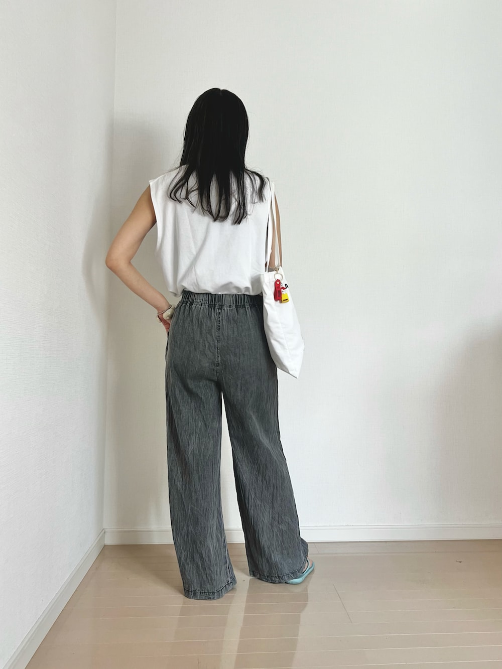 ブラック系のデニムパンツ、ホワイト系のTシャツ/カットソー、ブルー系のサンダルを着用したレディースの夏コーディネートの2枚目の写真