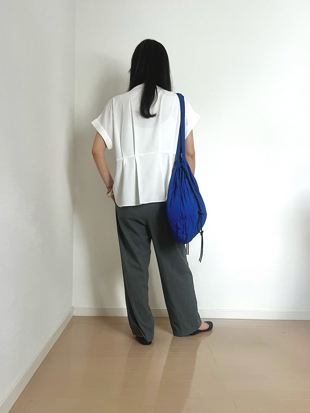 ホワイト系のシャツ/ブラウス、ブルー系のトートバッグ、グレー系のスラックスを着用したレディースの夏コーディネートの2枚目の写真