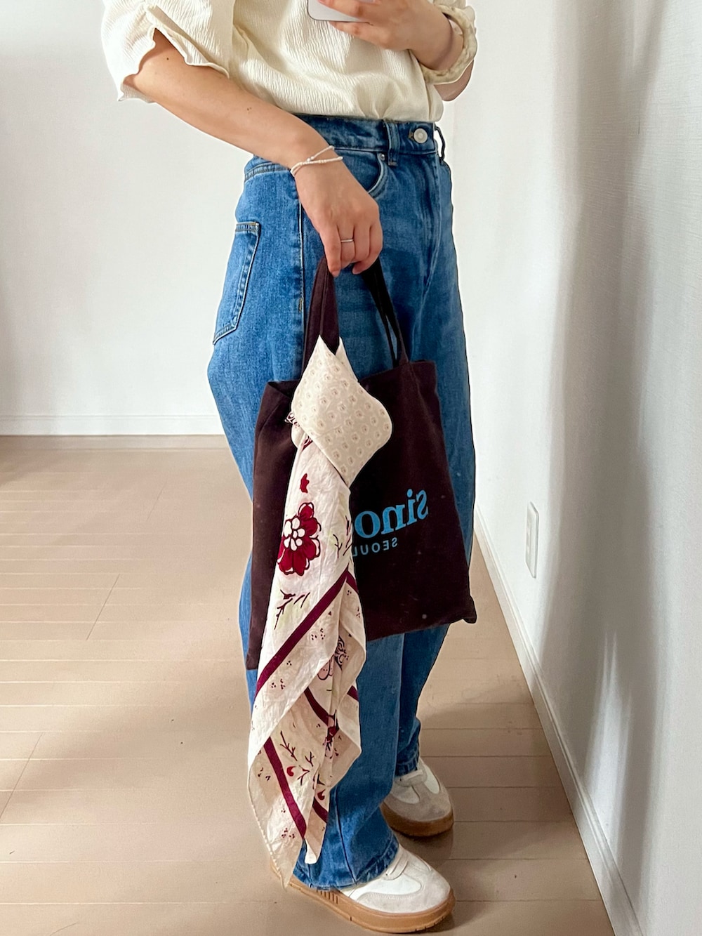 ブルー系のデニムパンツ、ホワイト系のTシャツ/カットソー、ブラウン系のエコバッグ/サブバッグを着用したレディースの夏コーディネートの2枚目の写真