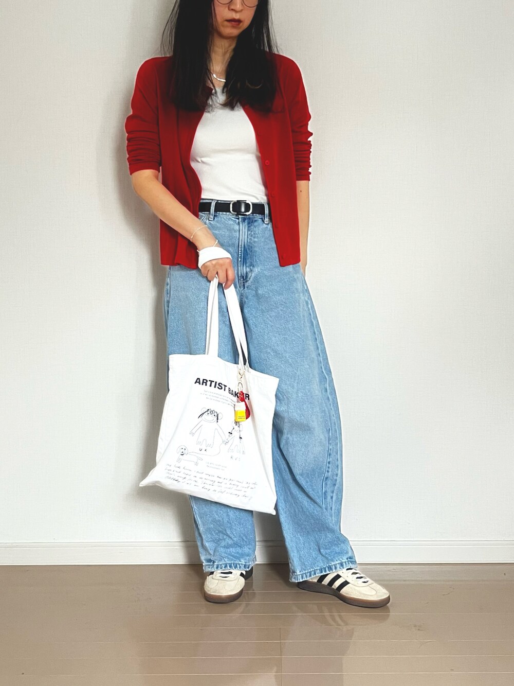 レッド系のカーディガン/ボレロ、ブルー系のデニムパンツ、ホワイト系のスニーカーを着用したレディースの春コーディネートの2枚目の写真