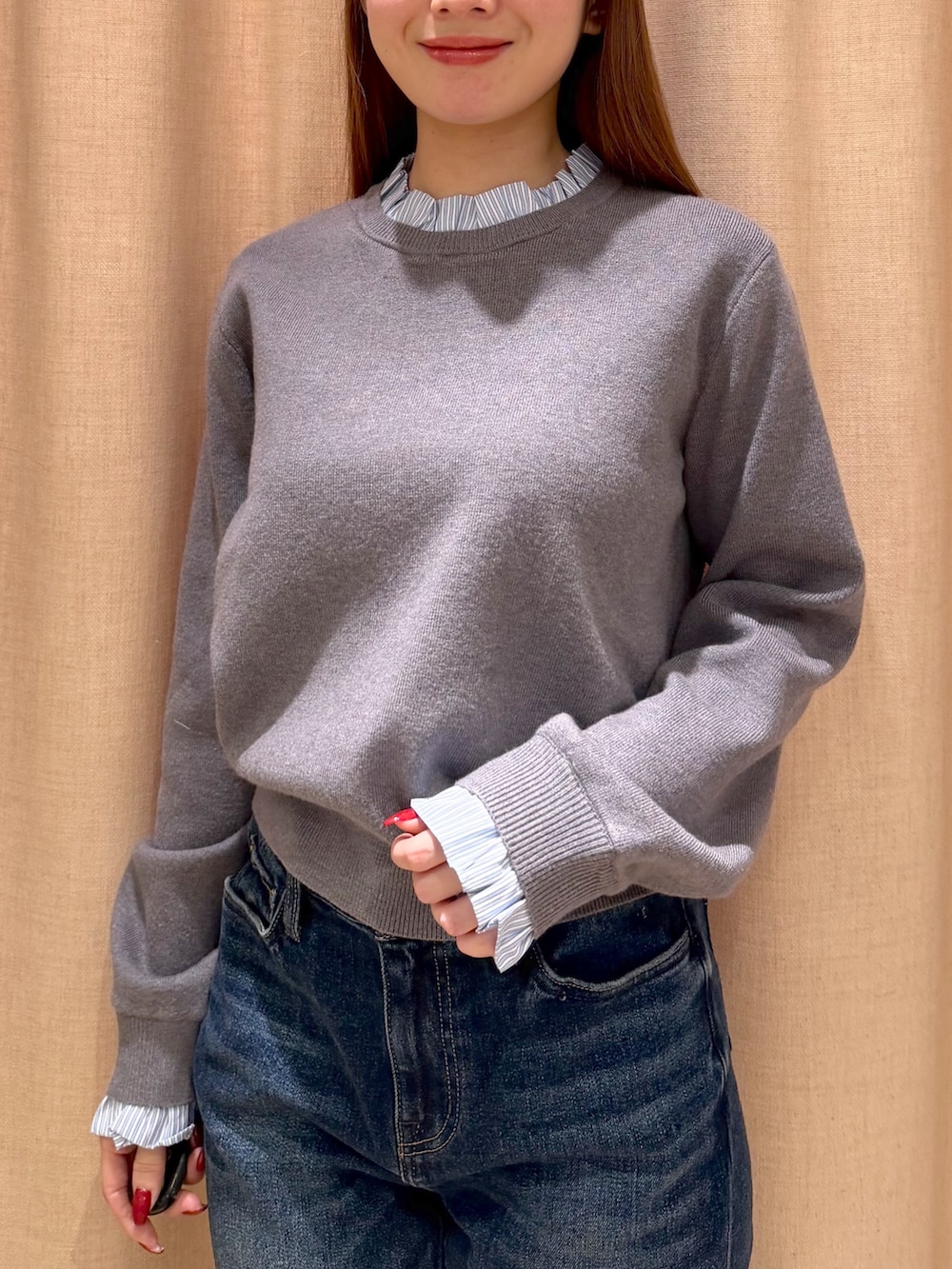 オレンジ系のボストンバッグ、ブルー系のデニムパンツ、グレー系のニット/セーターを着用したレディースの秋コーディネートの6枚目の写真