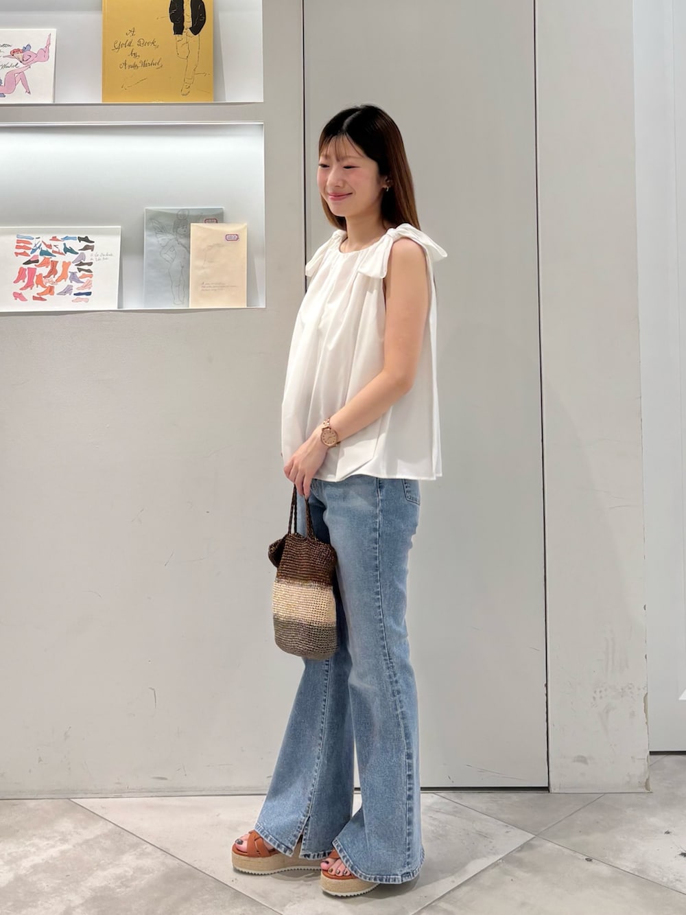 ホワイト系のシャツ/ブラウス、ゴールド系のハンドバッグ、ブルー系のデニムパンツを着用したレディースの夏コーディネートの3枚目の写真