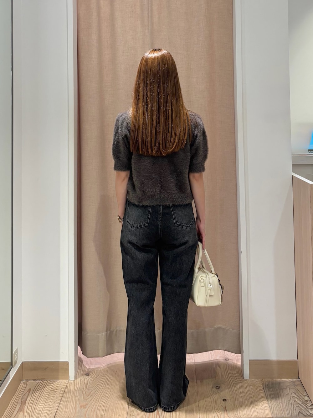 ブラック系のデニムパンツ、ホワイト系のボストンバッグ、グレー系のニット/セーターを着用したレディースの秋コーディネートの4枚目の写真