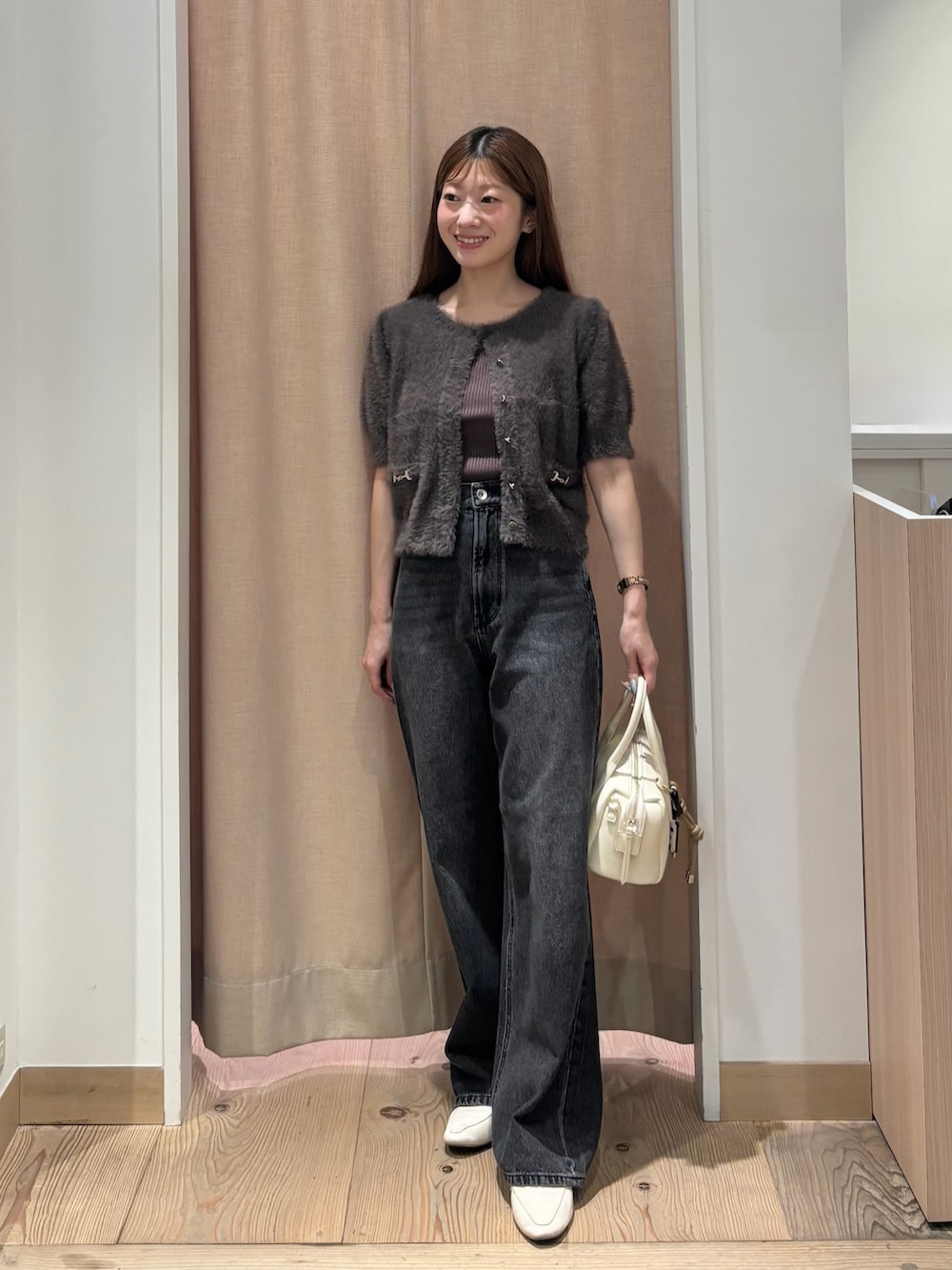 ブラック系のデニムパンツ、ホワイト系のボストンバッグ、グレー系のニット/セーターを着用したレディースの秋コーディネートの2枚目の写真