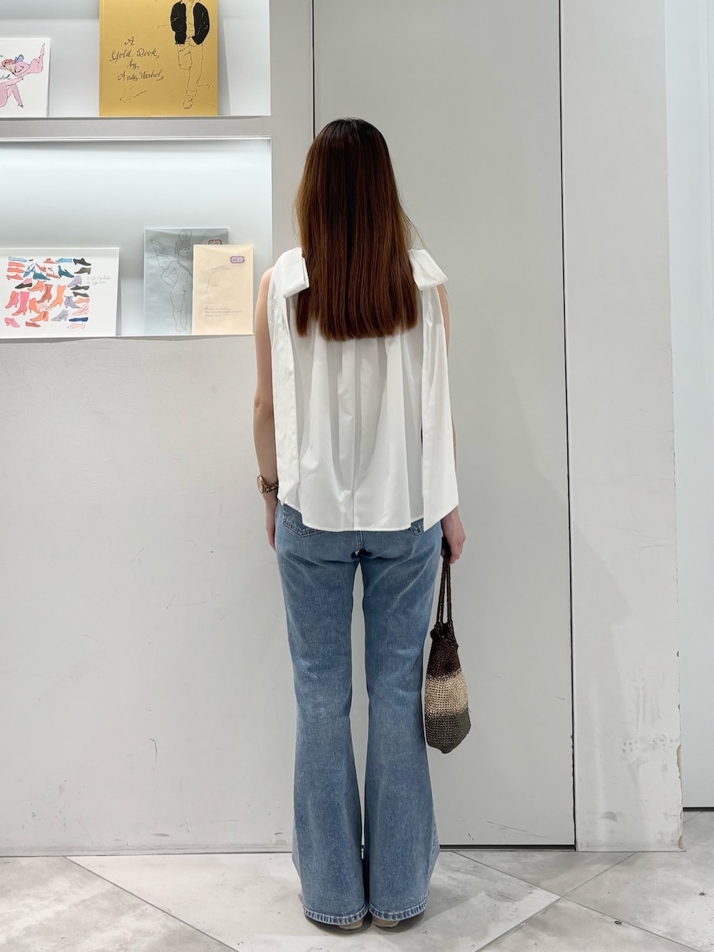 ホワイト系のシャツ/ブラウス、ゴールド系のハンドバッグ、ブルー系のデニムパンツを着用したレディースの夏コーディネートの5枚目の写真