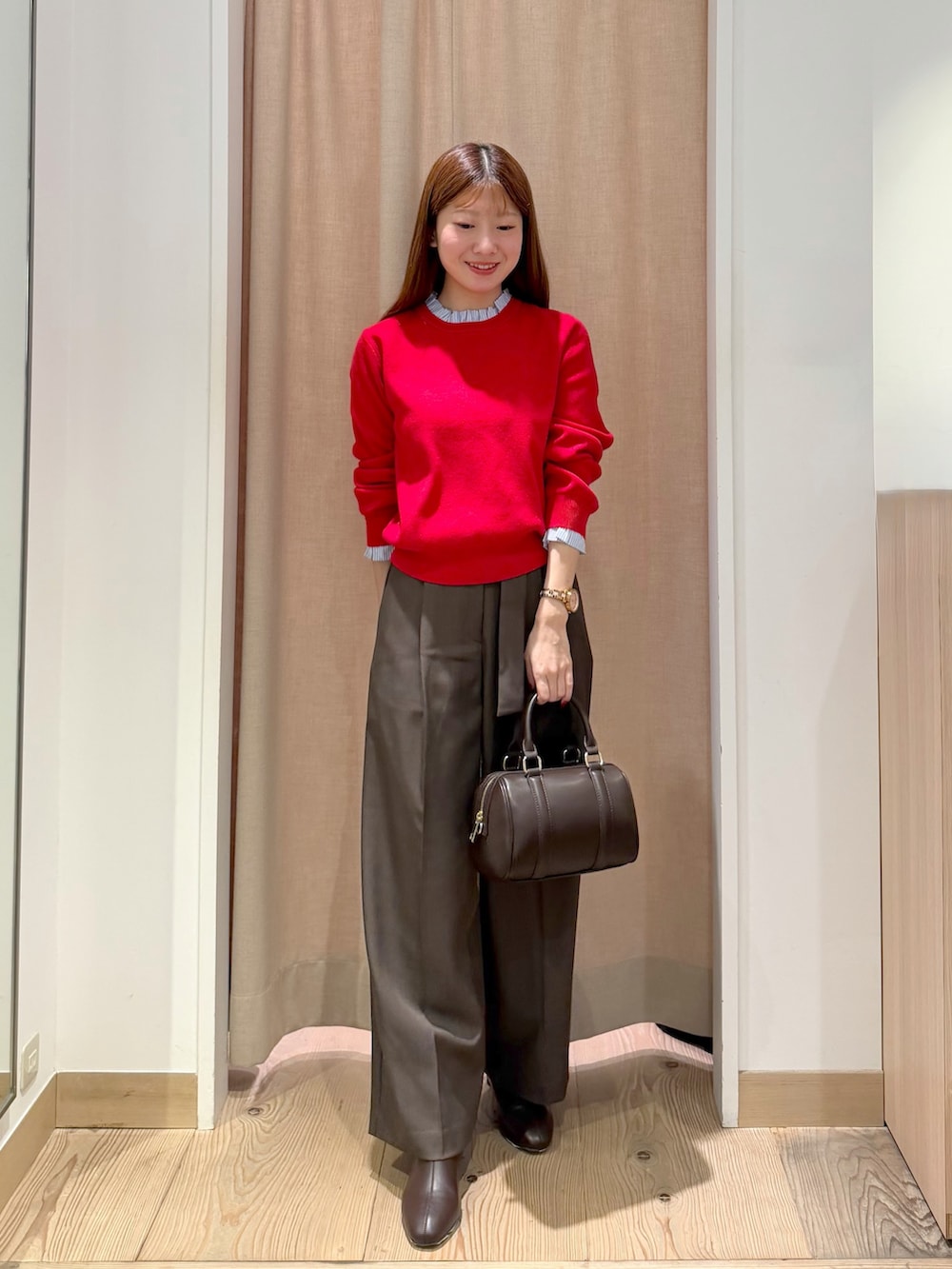 ブラウン系のその他パンツ、レッド系のニット/セーター、ブラウン系のボストンバッグを着用したレディースの秋コーディネートの2枚目の写真