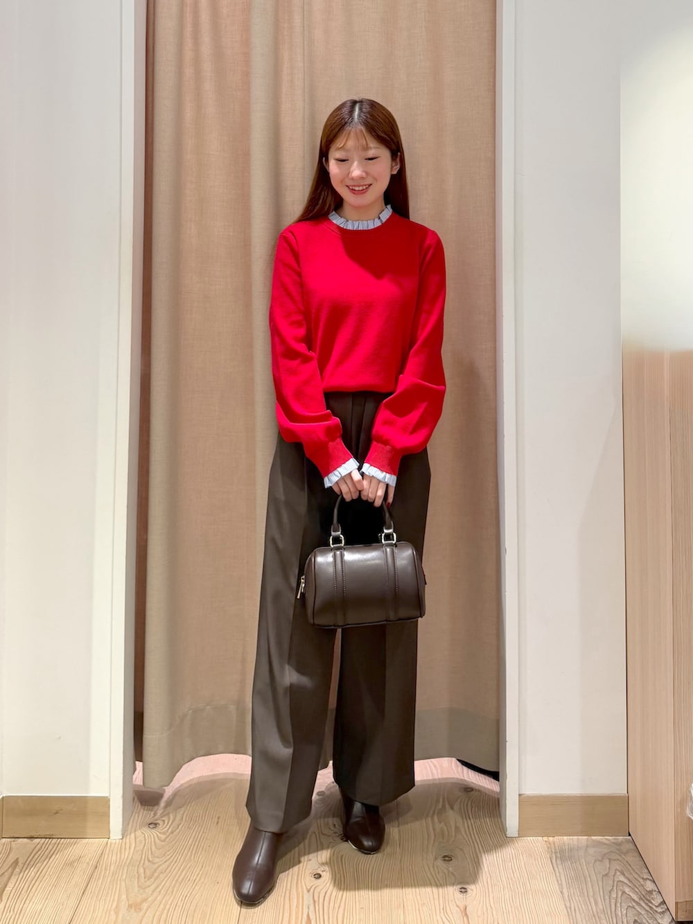 ブラウン系のその他パンツ、レッド系のニット/セーター、ブラウン系のボストンバッグを着用したレディースの秋コーディネートの4枚目の写真
