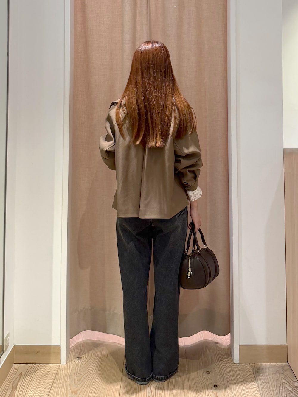 ブラック系のデニムパンツ、ブラウン系のボストンバッグ、ブラウン系のトレンチコートを着用したレディースの秋コーディネートの7枚目の写真