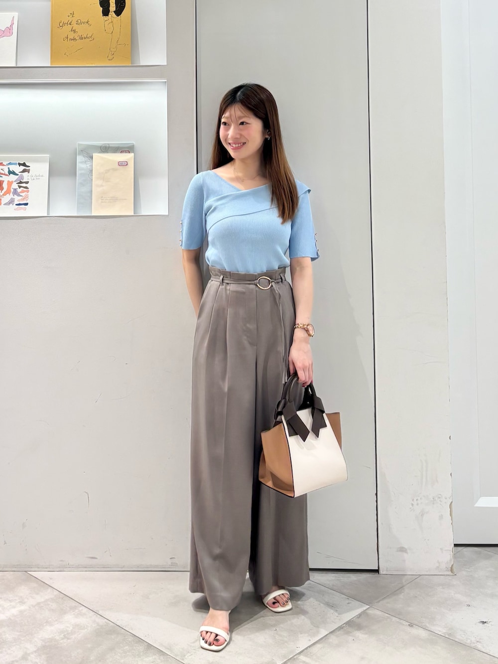 ブラウン系のその他パンツ、ホワイト系のトートバッグ、ブルー系のニット/セーターを着用したレディースの春コーディネートの2枚目の写真