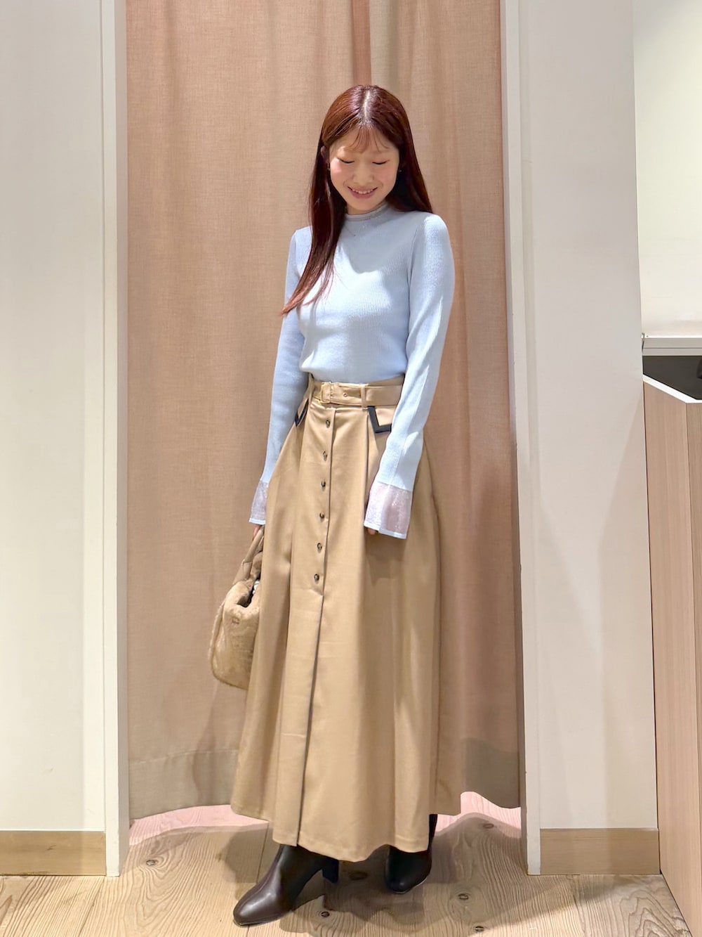 ベージュ系のスカート、ブルー系のニット/セーター、イエロー系のトートバッグを着用したレディースの秋コーディネートの3枚目の写真