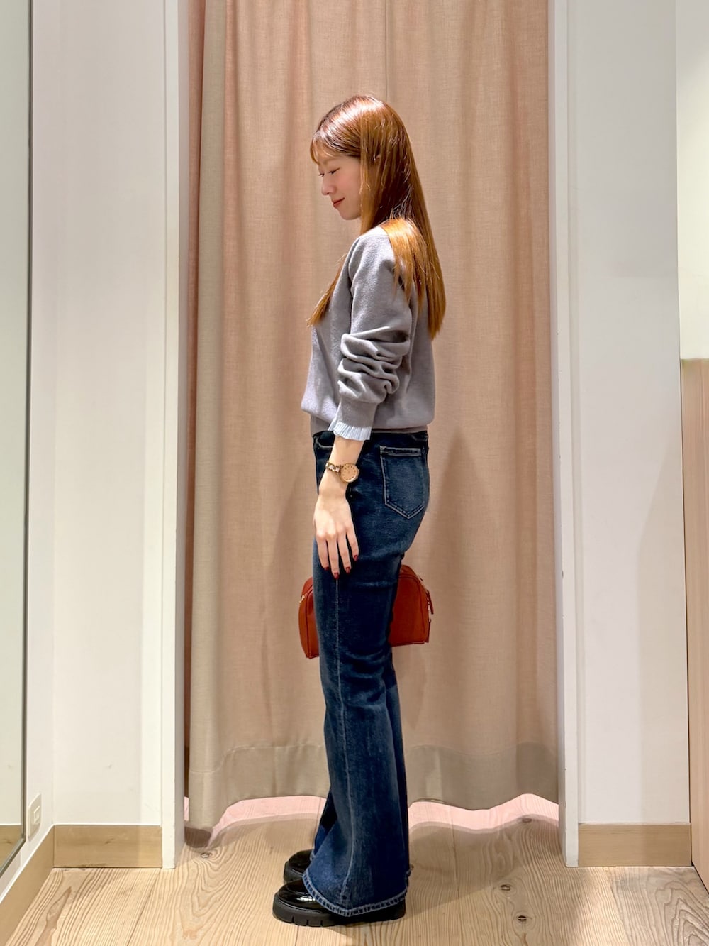 オレンジ系のボストンバッグ、ブルー系のデニムパンツ、グレー系のニット/セーターを着用したレディースの秋コーディネートの4枚目の写真