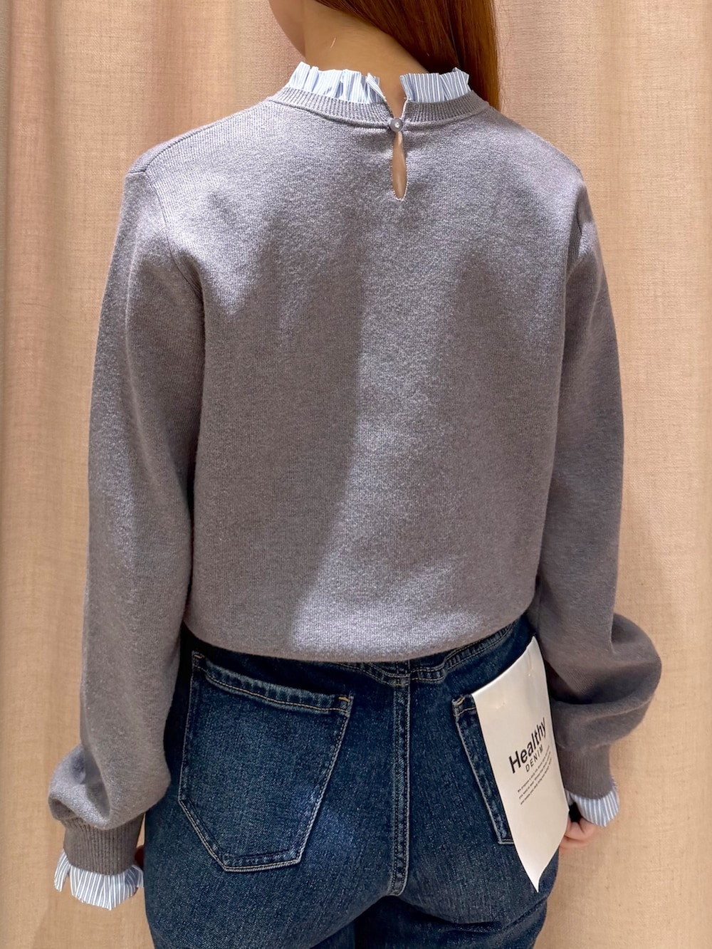オレンジ系のボストンバッグ、ブルー系のデニムパンツ、グレー系のニット/セーターを着用したレディースの秋コーディネートの7枚目の写真
