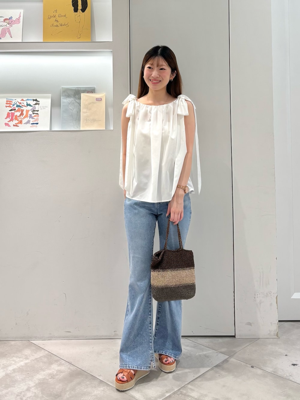 ホワイト系のシャツ/ブラウス、ゴールド系のハンドバッグ、ブルー系のデニムパンツを着用したレディースの夏コーディネートの2枚目の写真